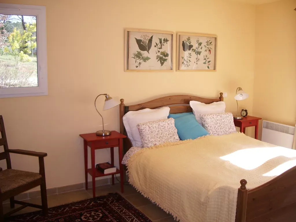 Slaapkamer met houten bed, botanische prenten en uitzicht op de tuin